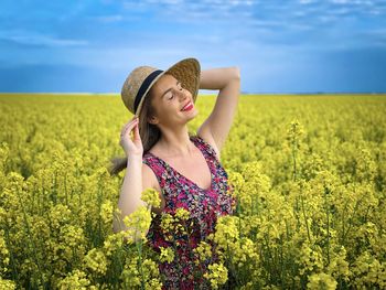 Beautiful young woman standing by flower field