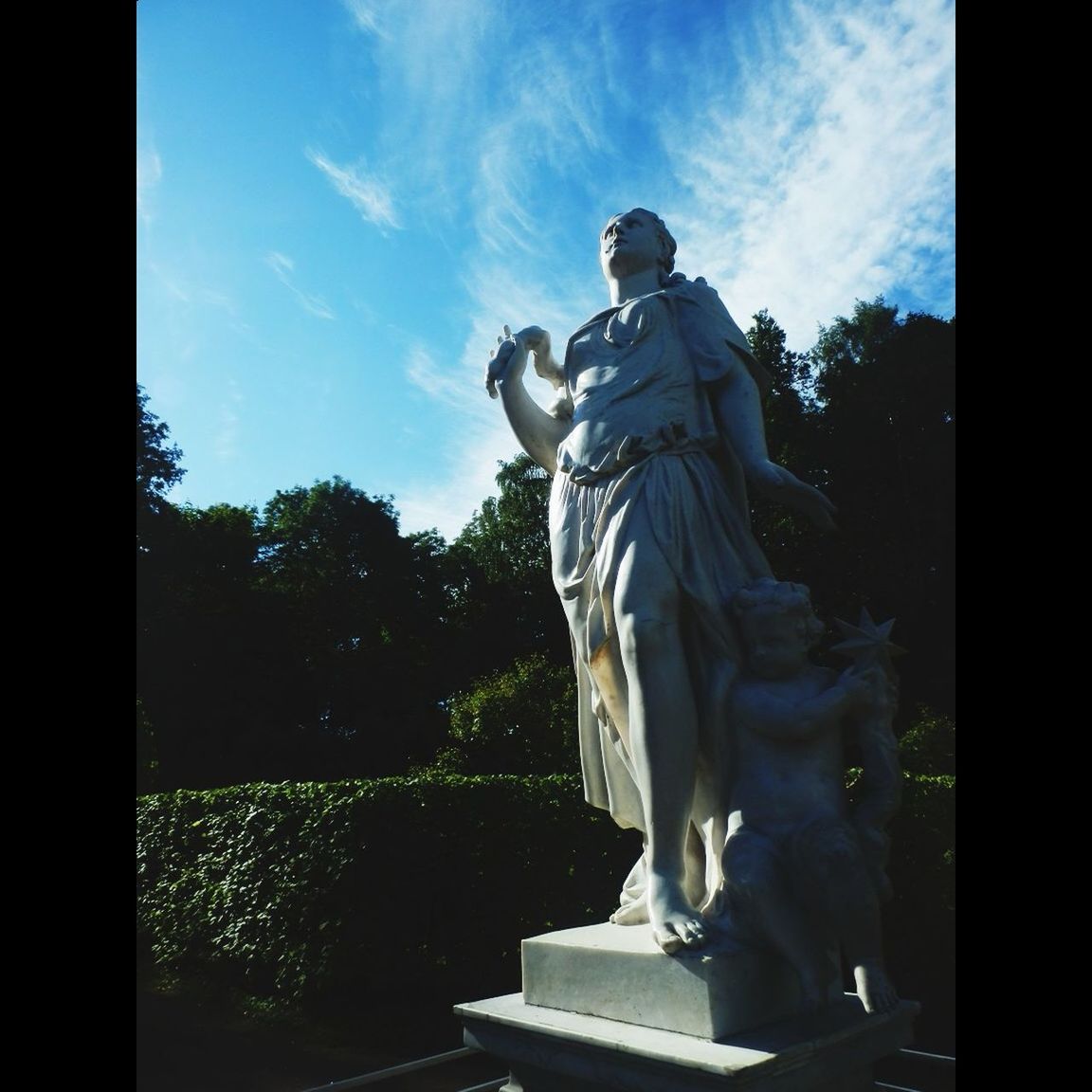 statue, sculpture, human representation, art and craft, art, creativity, sky, tree, low angle view, animal representation, cloud - sky, outdoors, sunlight, day, cloud, built structure, craft, no people