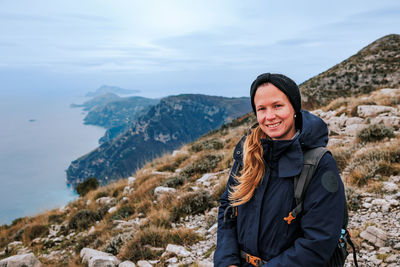 Portrait of young woman standing against mountain