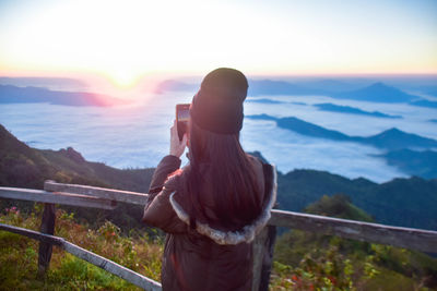 Rear view of man standing on railing against mountain