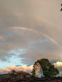 View of rainbow over building against cloudy sky
