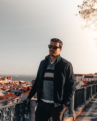 Young man wearing sunglasses standing against clear sky