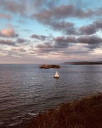 Scenic view of sea against cloudy sky during sunset