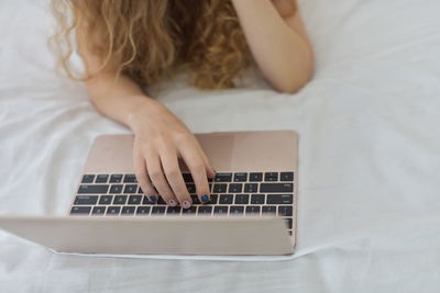 Midsection of woman using laptop while lying on bed