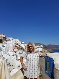 Portrait of smiling mature woman in town against clear sky during sunny day