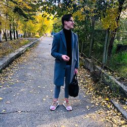 Smiling young man standing on footpath at park