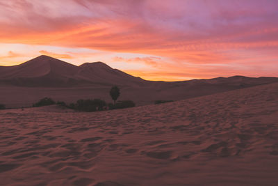 Sand dunes in desert against cloudy sky