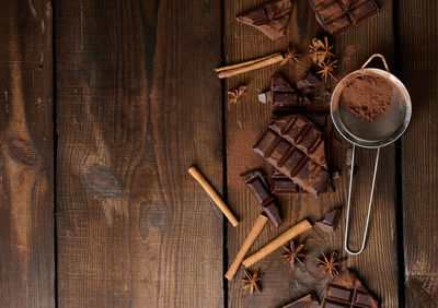 Broken pieces of dark chocolate, cinnamon sticks and star anise on a brown wooden 