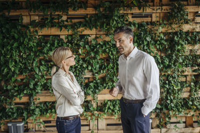 Businessman and businesswoman in green office talking