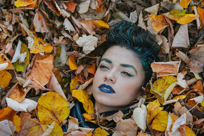 High angle view of thoughtful female model amidst autumn leaves