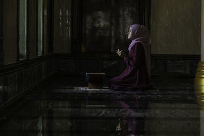 Side view of woman standing against wall in building