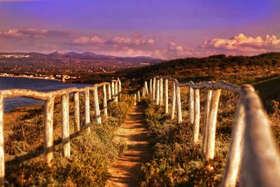 Wooden posts on field against sky during sunset