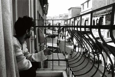 Man holding cigarette at balcony in city