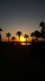 Silhouette palm trees against sky during sunset