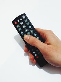 Cropped image of woman holding remote control over white background