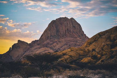 Rock formations on landscape against cloudy sky