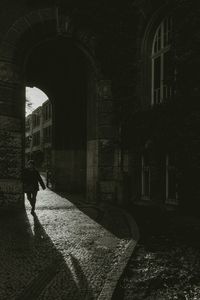 Rear view of man walking on street amidst buildings in city