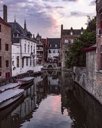 Canal amidst buildings against sky during sunset