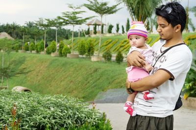 Rear view of mother with daughter standing against plants