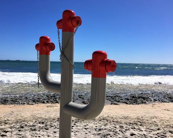 Red fire hydrant on beach against clear sky