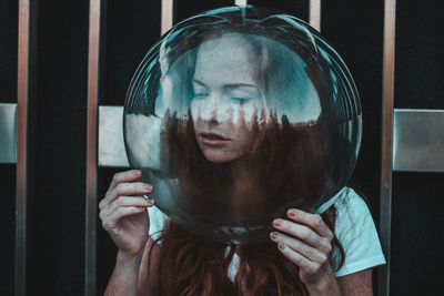 Close-up of thoughtful young woman wearing glass helmet in head against metallic railing