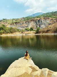 Woman sitting on rock by lake