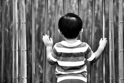 Rear view of boy standing by gate