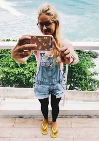 Full length of man photographing while standing on mobile phone