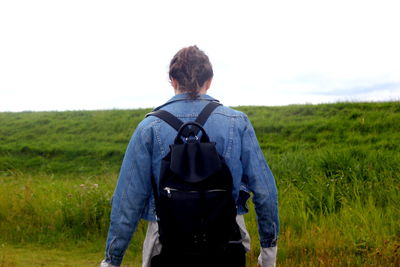 Rear view of man walking on field against sky