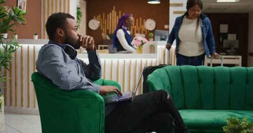 Side view of woman using mobile phone while sitting on sofa at home