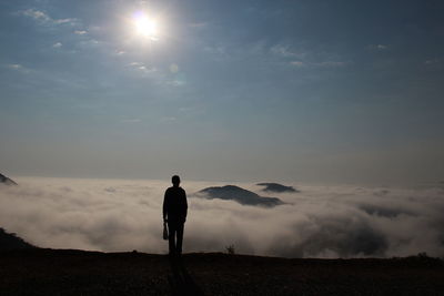 Rear view of man standing against cloudscape