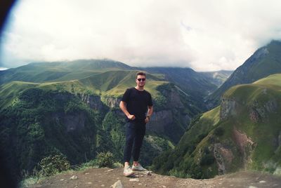 Young man standing on mountain against sky