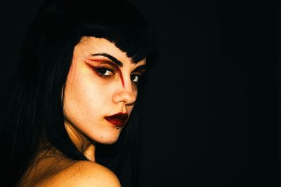 Side view portrait of serious young woman with eyeshadow against black background