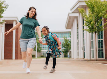 Young millennial mother sending daughter off back to school