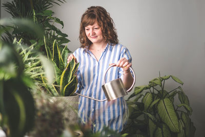 Portrait of young woman standing against plants