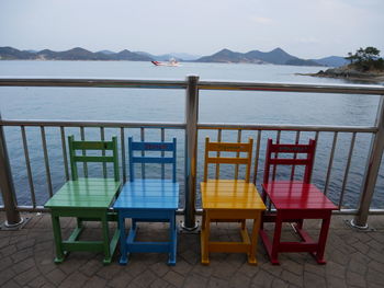 Chairs and table by sea against sky