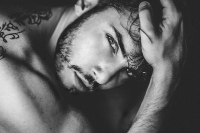 Close-up portrait of shirtless young man lying on bed