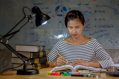 Woman studying with school supplies on table at home