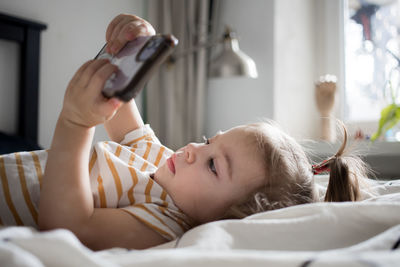 Young woman using mobile phone on bed at home