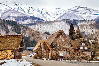 Snow covered houses by buildings against sky