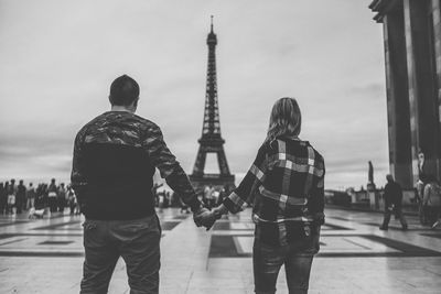 Rear view of couple holding hands with eiffel tower in background