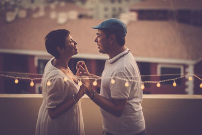 Side view of couple holding hands while standing in balcony