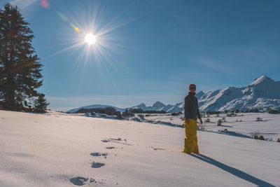 A full-body shot of a young caucasian woman standing in the french alps mountains