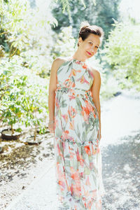 Happy multiracial japanese woman in romantic floral maxi dress in summer park