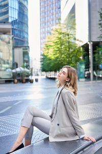 Portrait of young woman sitting on street in city