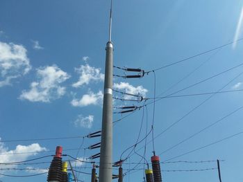 Low angle view of electricity pylon against blue sky