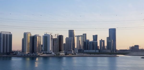 Sea by modern buildings against sky in city