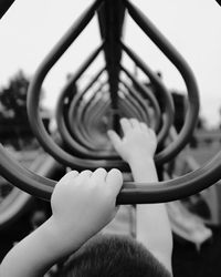 Cropped image of boys holding monkey bars in playground