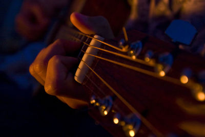 Midsection of man playing guitar at music concert