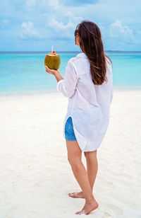 Rear view of woman standing at beach